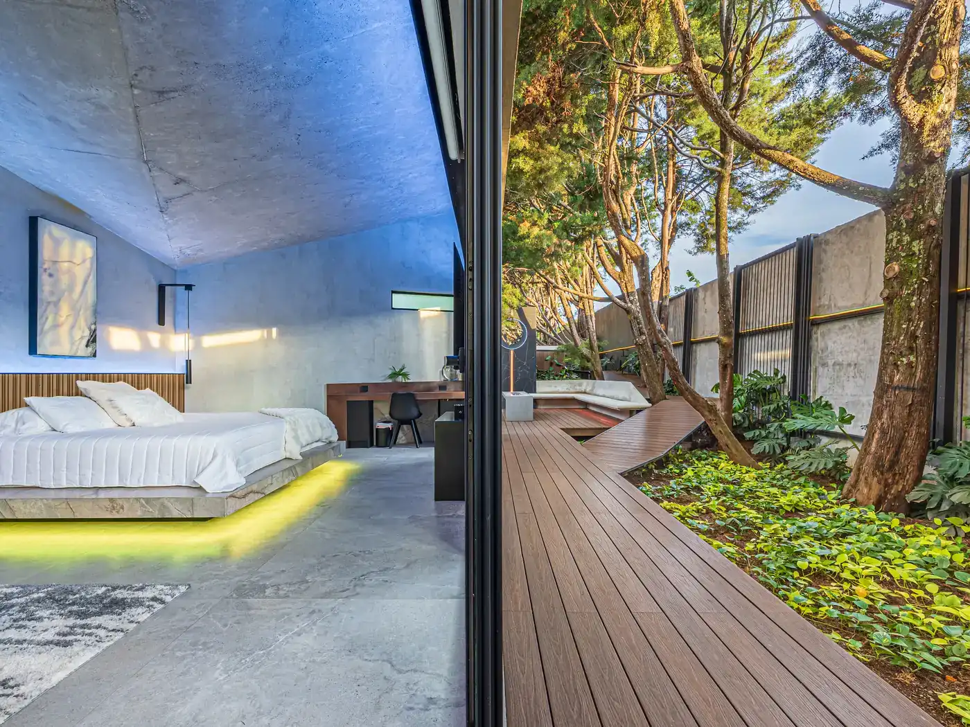 Habitación de Nebulae con la cama junto al ventanal abierto a una terraza de madera y un árbol