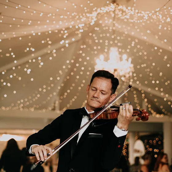 Violinista tocando en vivo bajo el techo de luces del salón