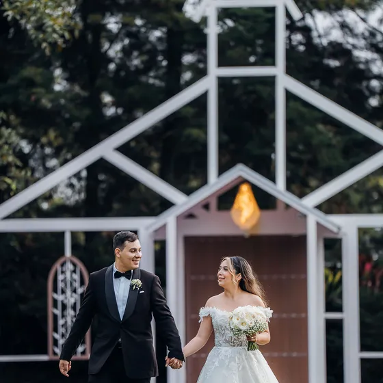 Novios caminando sobre el prado con la Fachada de la Iglesia detrás