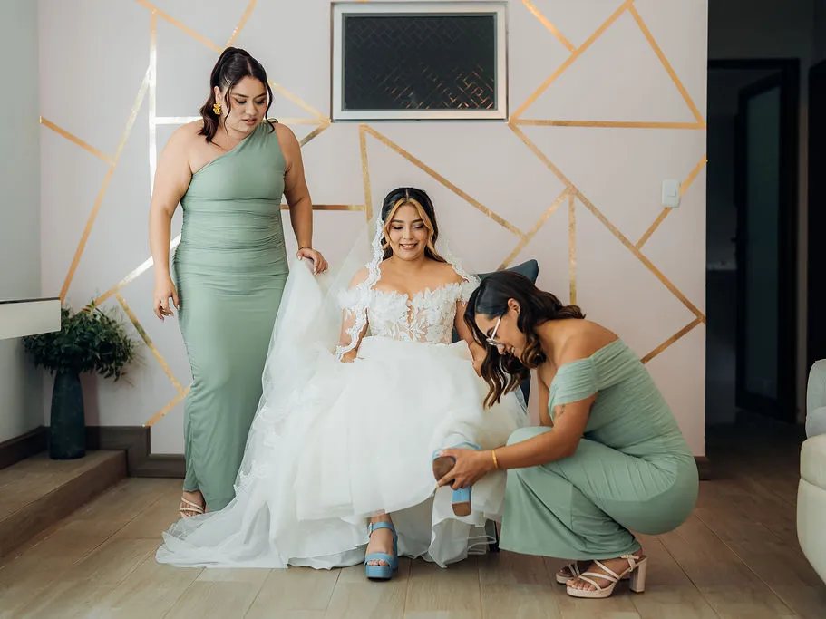 Novia acompañada por sus damas mientras terminan de ajustar el vestido