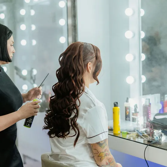 Estilista aplicando fijador al peinado de la novia en el Salón de Maquillaje