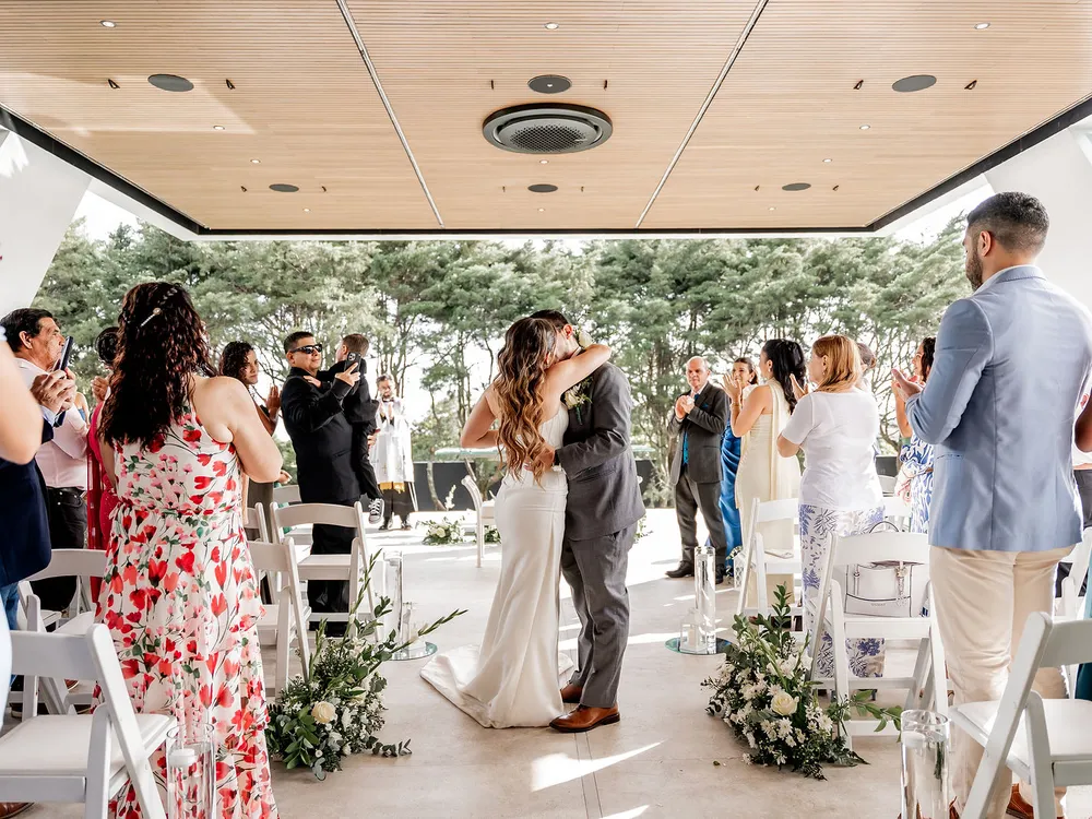 Beso de los novios rodeados por los invitados al terminar la ceremonia en Nebulae