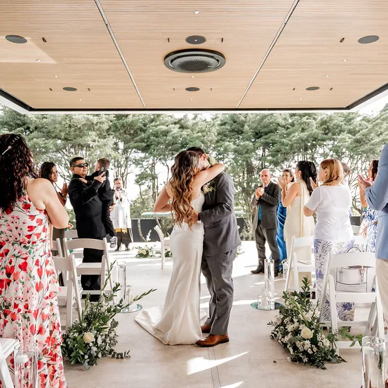 Beso de los novios rodeados por los invitados al terminar la ceremonia