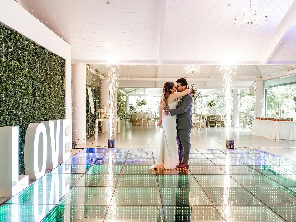 Invitados bailando sobre la pista LED del salón con los ventanales abiertos