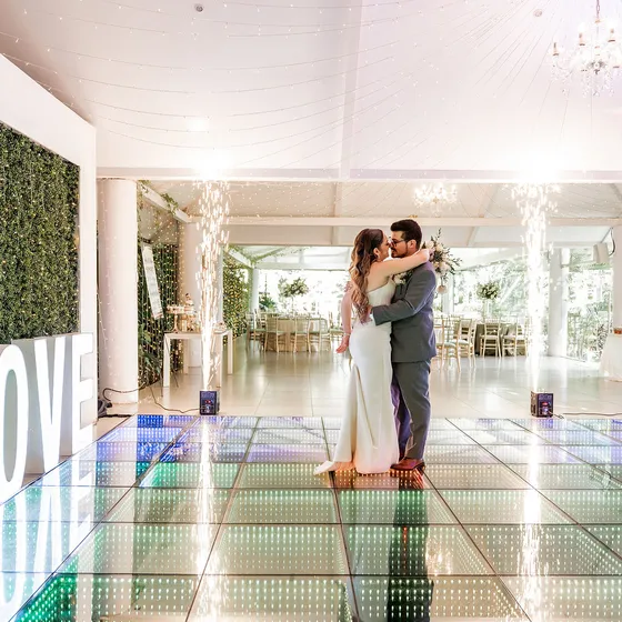 Novios bailando sobre la pista LED del salón con los ventanales abiertos