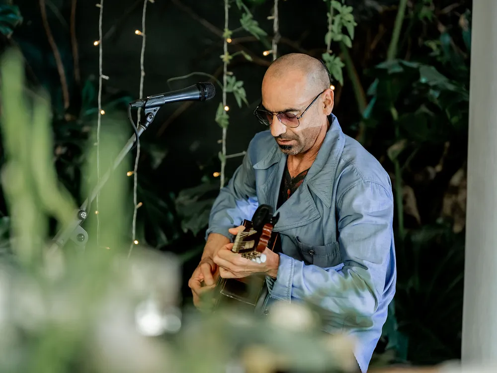 Guitarrista tocando en vivo entre las plantas del salón durante la cena