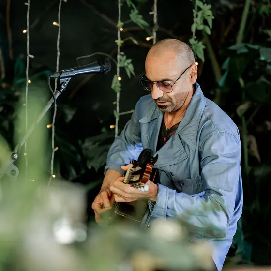 Guitarrista tocando en vivo entre las plantas del salón