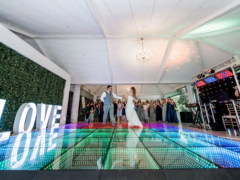 Invitados bailando junto a las letras iluminadas LOVE sobre la pista LED