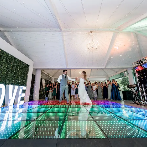 Novios bailando junto a las letras iluminadas LOVE sobre la pista LED